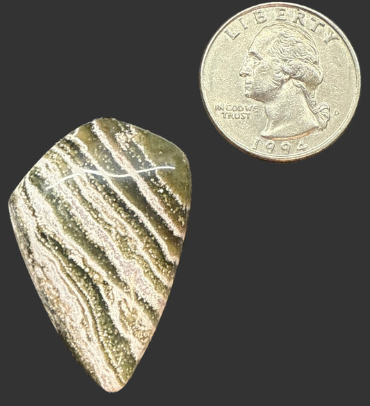 Rock next to a coin on a dark surface