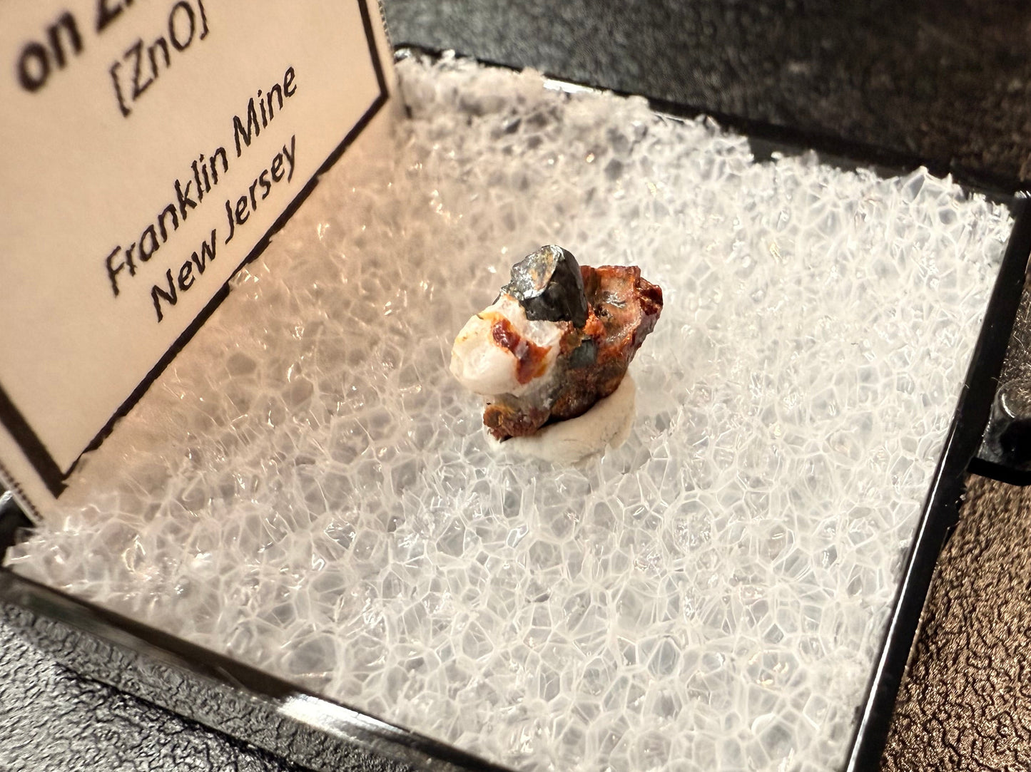 Mineral sample on a display card with text about Franklin Mine, New Jersey