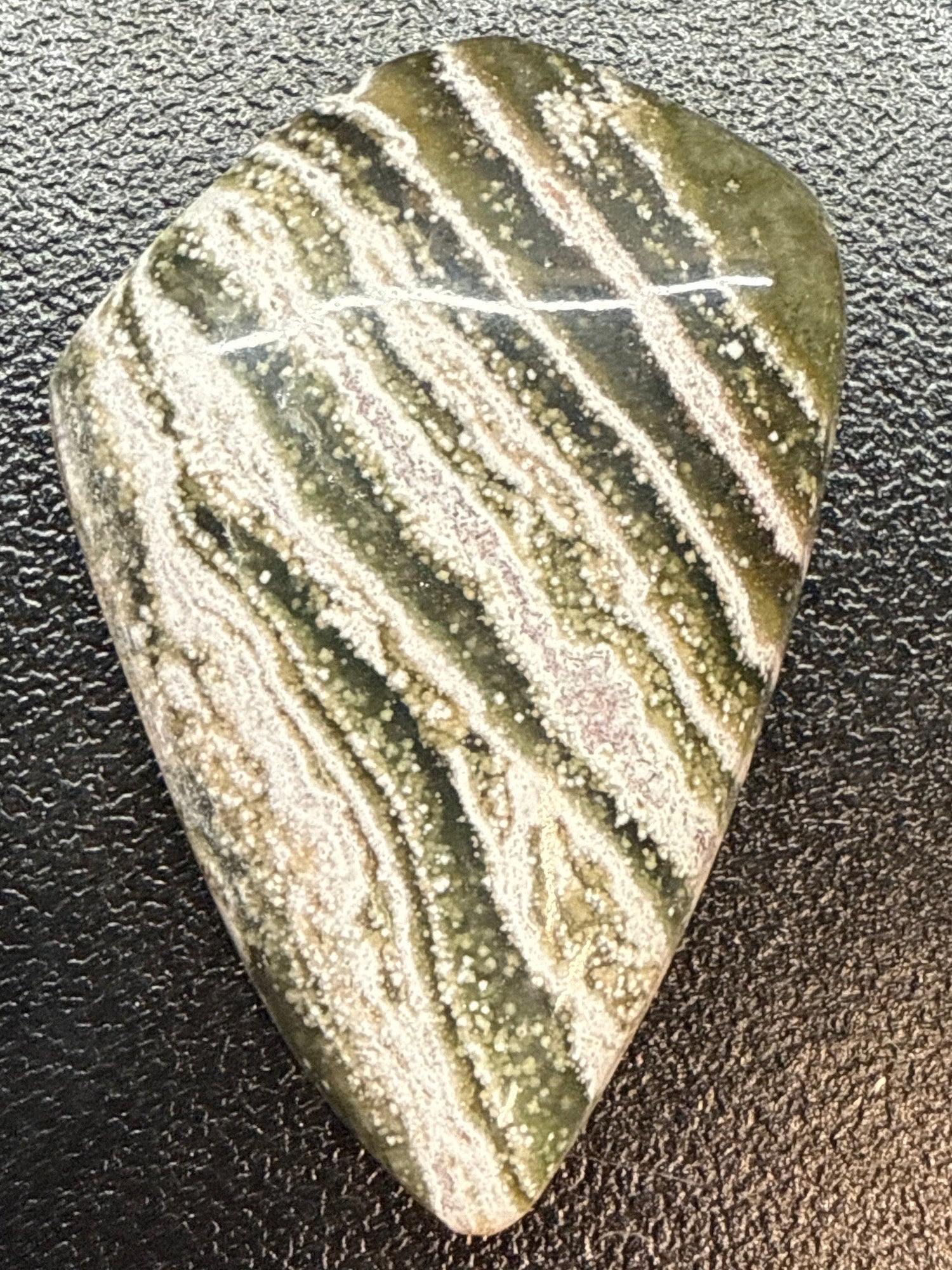 Polished stone with zebra pattern on a dark textured surface
